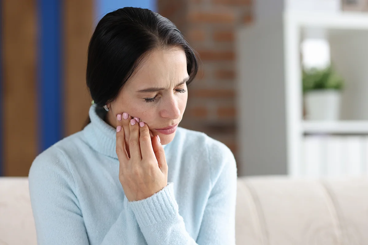 woman holding her cheek area sore tooth diagnosis treatment pulpitis concept